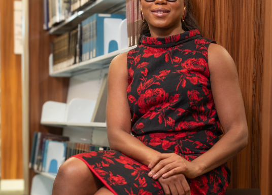 Abbey Fajimolu sitting down with legs crossed in library