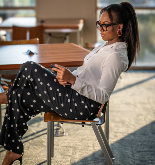 Abbey Fajimolu sitting on a chair looking at her phone.