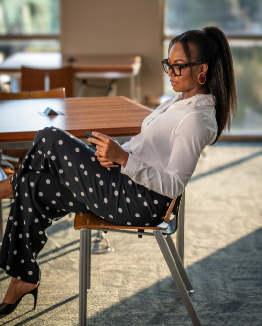 Abbey Fajimolu sitting on a chair looking at her phone.