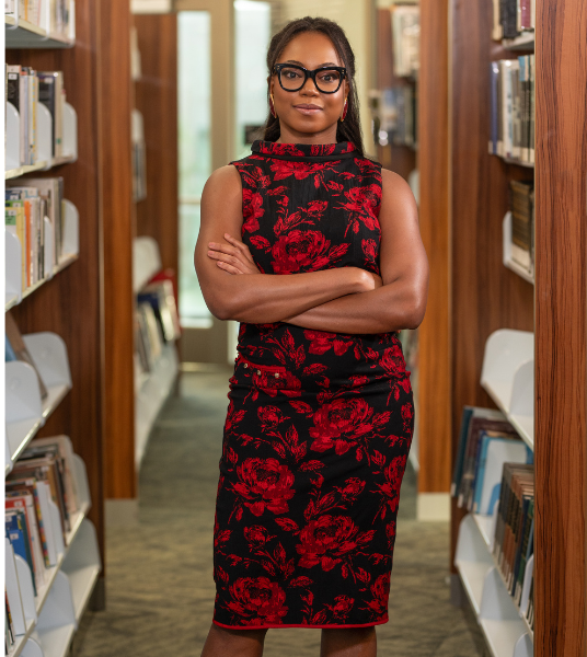 Abbey Fajimolu standing in library with arms crossed